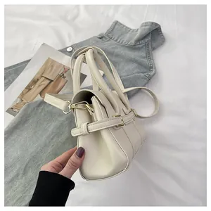 Détail du profil latéral du sac bandoulière beige avec finitions métalliques dorées chic