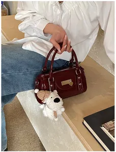 Detail der weinroten Lackleder-Bowlingtasche mit silbernen Beschlägen und Hundeanhänger