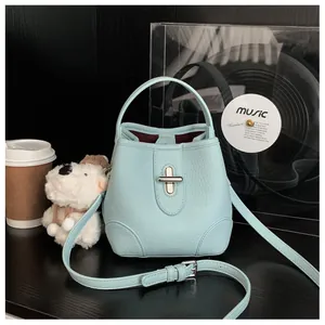 Detail of light blue bucket bag with pebble leather texture and silver cross lock