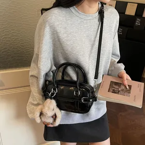 Minimalist black glossy bowling bag with rabbit charm and adjustable shoulder strap