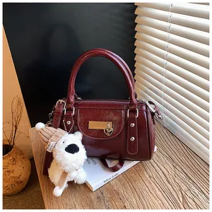 Detail der dunkelroten glänzenden Bowling Bag mit Herzanhänger und Plüschhund-Anhänger