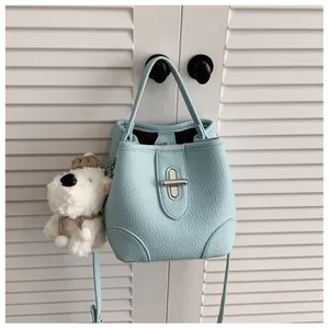 Detail of light blue bucket bag with silver twist lock and plush puppy keychain