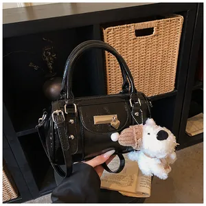 Detail der glänzenden schwarzen Lackleder-Bowlingtasche mit Plüschhund-Anhänger