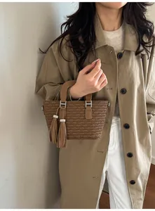 Brown pleated bucket bag detail with silver H-shaped hardware and dual leather tassels