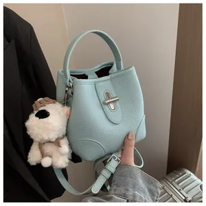 Detail of light blue bucket bag with pebble leather texture and cute puppy charm
