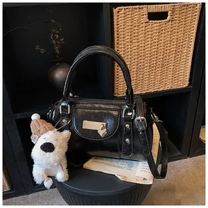 Detail der schwarzen glänzenden Bowlingtasche mit Herz-Metallanhänger und Plüschhund-Anhänger