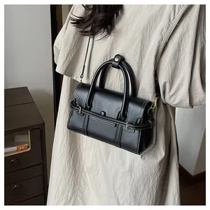 Détail du sac en cuir mat noir avec coutures contrastées blanches et boucles dorées