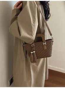 Detail of dark brown pleated bucket bag with tassel accent worn cross-body by a model