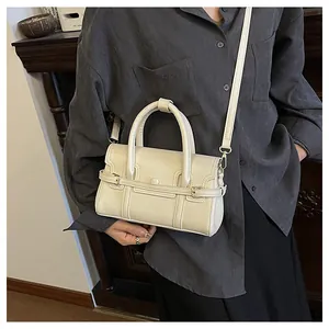 Sac à main chic en cuir crème avec boucles dorées sur un mannequin pour un look vintage