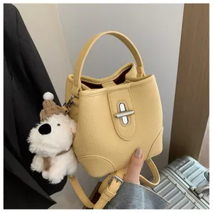 Close-up of yellow pebble leather bucket bag with silver twist lock and puppy charm
