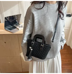 Detail of black pleated PU leather bucket bag with tassel charm and U-shaped handle