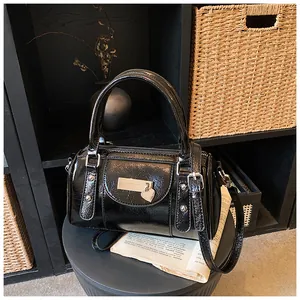 Detail der schwarzen Lackleder-Tasche mit silbernen Nieten und Herz-Metallanhänger