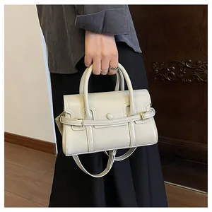 Détail du sac à main en cuir crème avec poignées cylindriques et boucle dorée