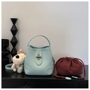 Detail of light blue bucket bag with silver twist lock and red drawstring inner pouch