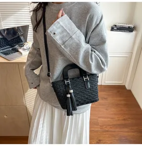 Detail of black pleated leather handbag with tassels and silver metal hardware