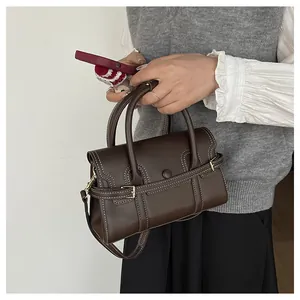 Détail du sac à main en cuir marron foncé avec surpiqûres blanches et boucle métallique