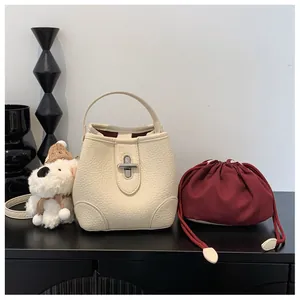 Detail of cream bucket bag with lychee pattern leather and silver turn-lock closure