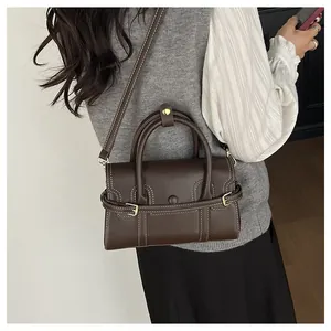 Gros plan du sac à main rétro marron foncé avec coutures blanches et doubles boucles