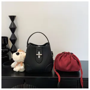 Close-up of black litchi leather bucket bag featuring a silver twist lock and red liner