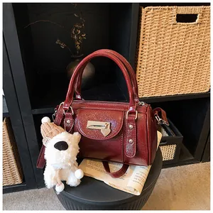 Detail der burgunderroten Lacktasche mit silbernen Beschlägen und Plüsch-Welpenanhänger