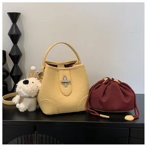 Detail of pale yellow pebbled leather bucket bag with silver lock and plush puppy charm