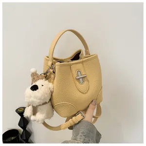 Close-up of beige bucket bag with lychee texture and cute plush puppy keychain
