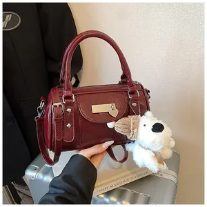 Detail der weinroten Lackleder-Tasche mit silbernen Beschlägen und Plüschwelpen-Anhänger