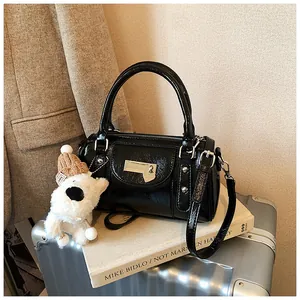 Detail der schwarzen glänzenden Bowlingtasche mit Herzschloss und süßem Welpenanhänger