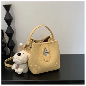 Close-up of pale yellow lychee leather bucket bag with silver twist lock and puppy charm