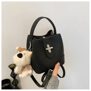 Close-up of black litchi leather bucket bag featuring silver lock and cute puppy charm