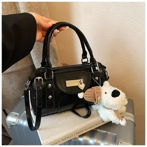 Detail der schwarzen glänzenden Boston Bag mit Nieten und Plüschanhänger auf Koffer