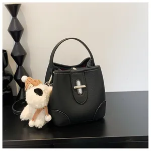 Detail of black lychee leather bucket bag with silver twist lock and puppy charm