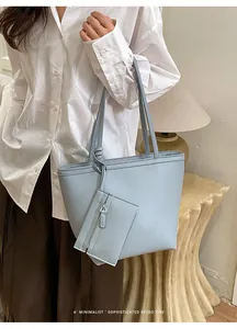 Κοντινό πλάνο γαλάζιας δερμάτινης τσάντας tote με ασορτί κρεμαστό κόσμημα σε μοντέλο