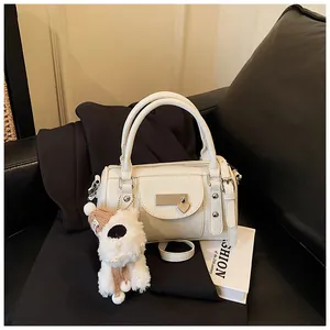 Detail der cremeweißen Boston Bag mit Herzanhänger und Plüschhund-Accessoire