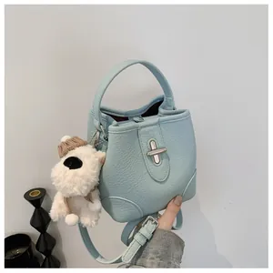 Close-up of light blue bucket bag with silver twist lock and white puppy charm detail