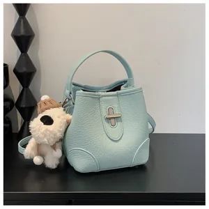 Detail of mint blue bucket bag with pebble leather texture and cute plush puppy charm