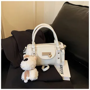 Detail einer weißen Boston Bag mit Herz-Metallschnalle, Nieten und Plüschhund-Anhänger