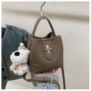 Close-up of brown bucket bag showing lychee grain leather texture and puppy charm