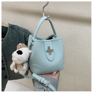 Light blue bucket bag with leather texture, turn-lock closure and plush puppy charm
