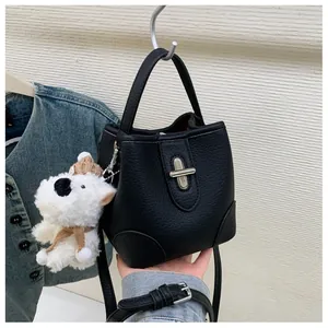 Close-up of black litchi leather bucket bag featuring a silver twist lock and puppy charm