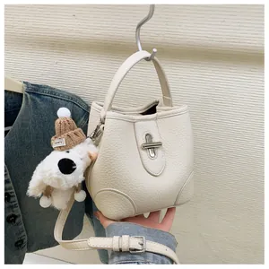 Detail of creamy white pebble leather bucket bag with silver turn-lock and cute bear charm