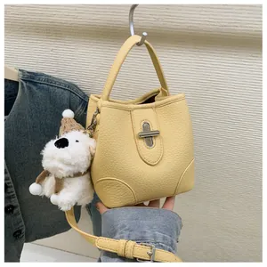 Detail view of yellow bucket bag with lychee texture and cute plush puppy charm