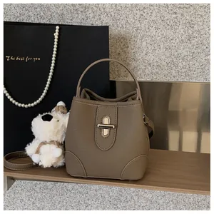 Detail of taupe bucket bag showing pebble leather texture and metal twist lock closure