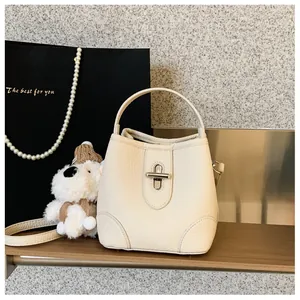 Detailed view of cream leather bucket bag with silver turn-lock and lychee texture