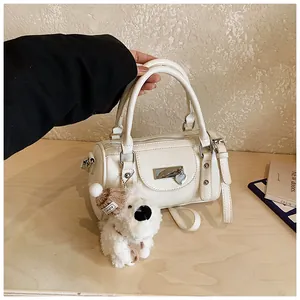 Detailansicht der weißen Leder-Boston-Bag mit Plüschwelpen-Anhänger und Herz-Detail