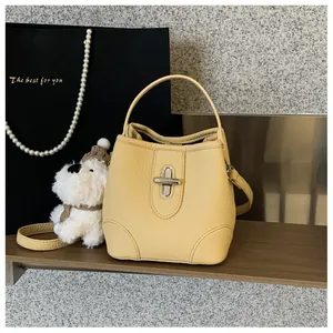 Detail of yellow bucket bag with silver twist lock and lychee leather texture