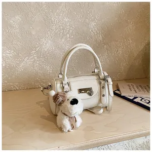 Details der weißen Zylindertasche mit Lederstruktur und süßem Plüsch-Hundeanhänger