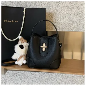 Close-up of black lychee grain leather bucket bag with golden twist lock and top handle