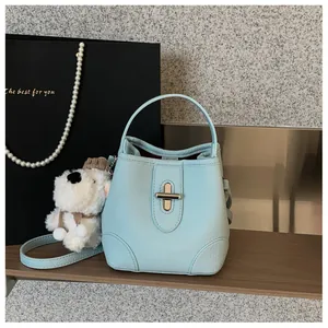 Close-up of light blue bucket bag with silver turn-lock and cute plush puppy charm