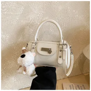 Detail der cremeweißen Boston Bag mit Plüschhund-Anhänger und silbernen Beschlägen